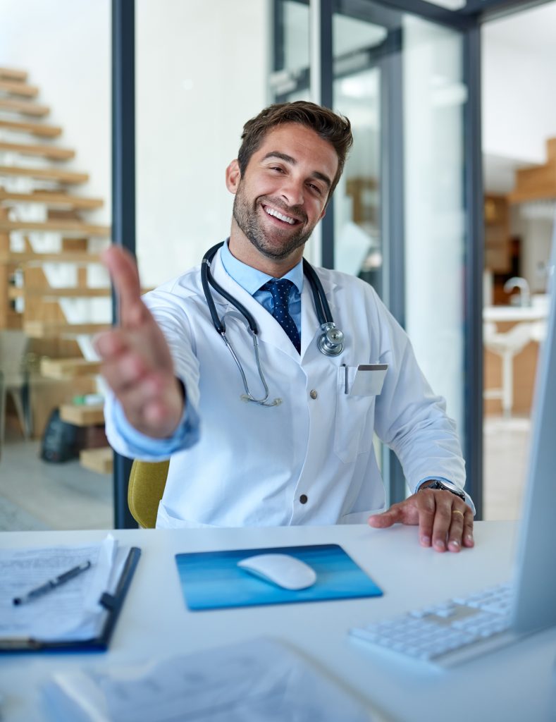 a young doctor extending a handshake in his office